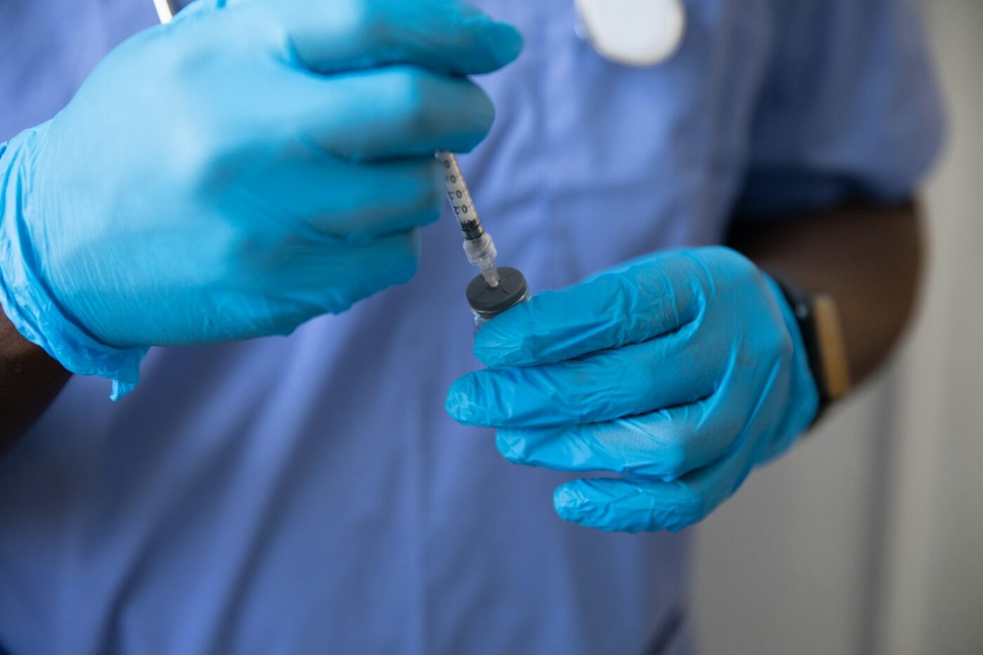 Verpleegkundige bereidt een injectie voor aan een werkblad op de afdeling