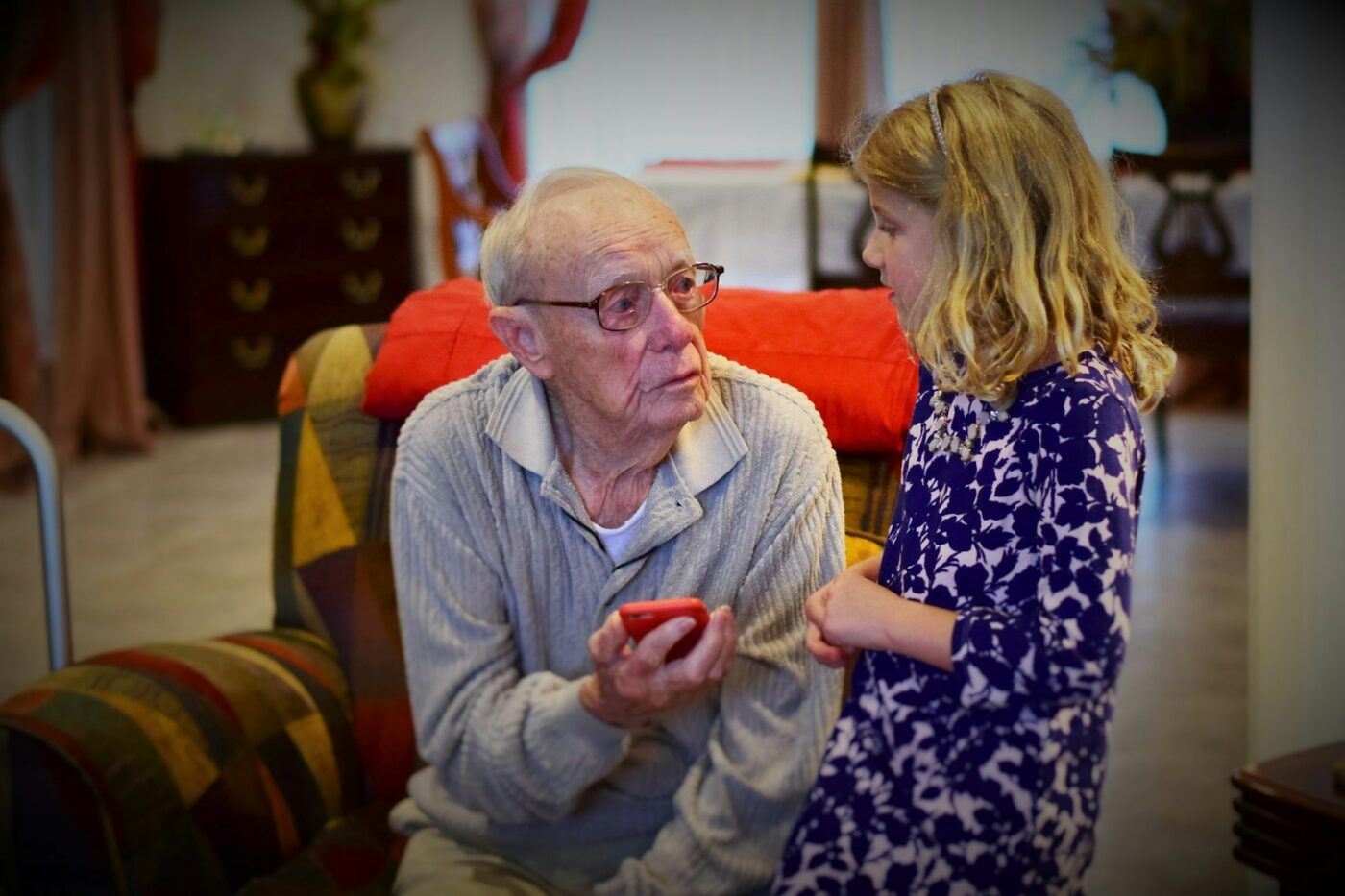 Vrouw helpt haar oudere vader met zijn jas in de gang van zijn huis
