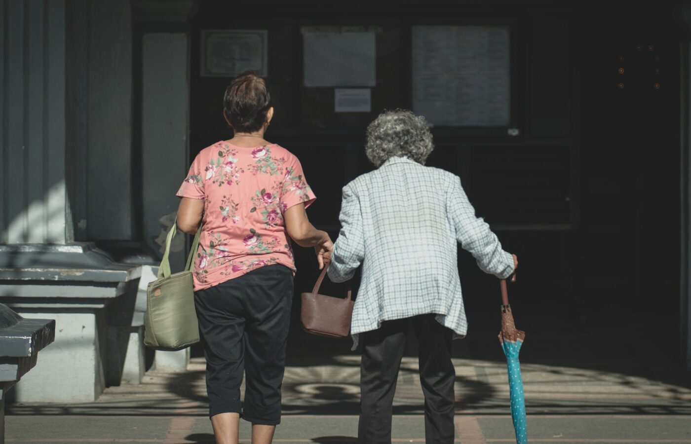 Verzorgende helpt een oudere vrouw met een rollator in de gang