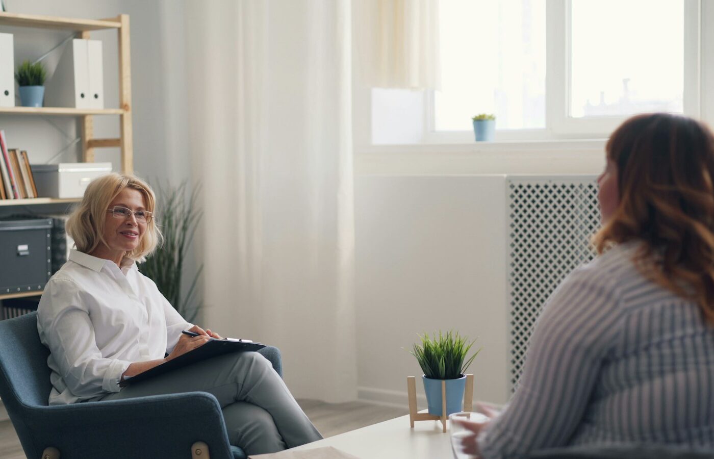 Psycholoog in gesprek met een oudere vrouw in een rustige kamer van een zorginstelling
