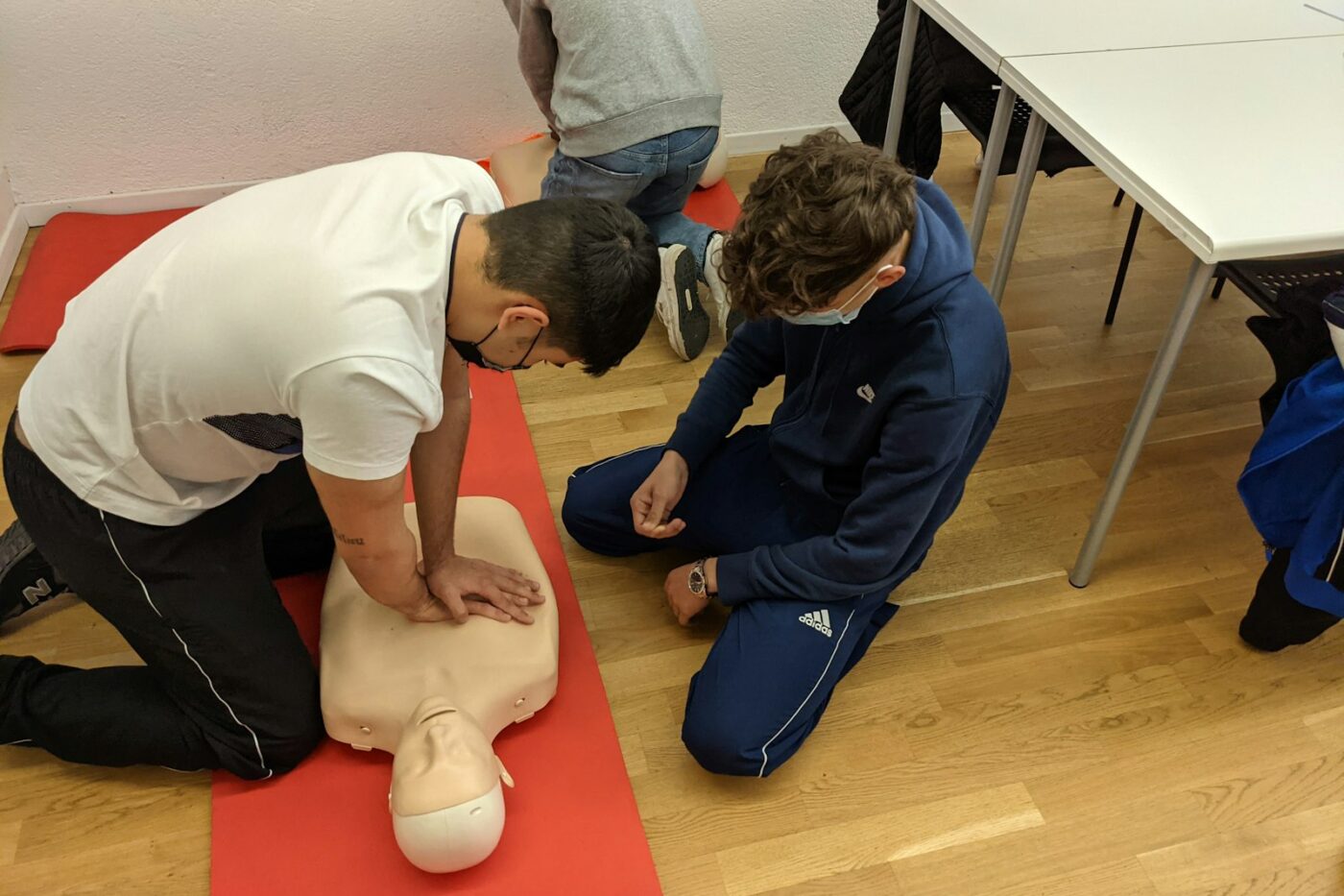 Zorgmedewerkers oefenen borstcompressies op een reanimatiepop tijdens een training