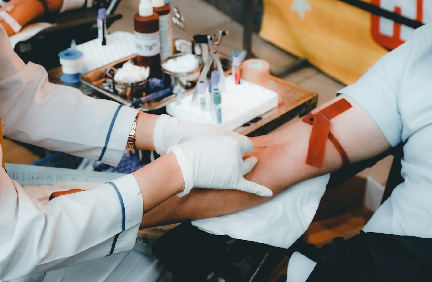 Verpleegkundige neemt bloed af uit de arm van een patiënt met een stuwband en buisjes